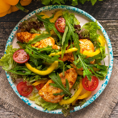 Chicken salad on a plate. Roasted chicken with fresh vegetables and lettuce. Top view. Closeup