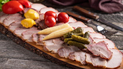 Meat appetizer. Smoked meat with marinated vegetables on wooden board.