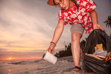 Asian women tourists picking up plastic garbage cleaning on the beach During the sunset . Tourists...