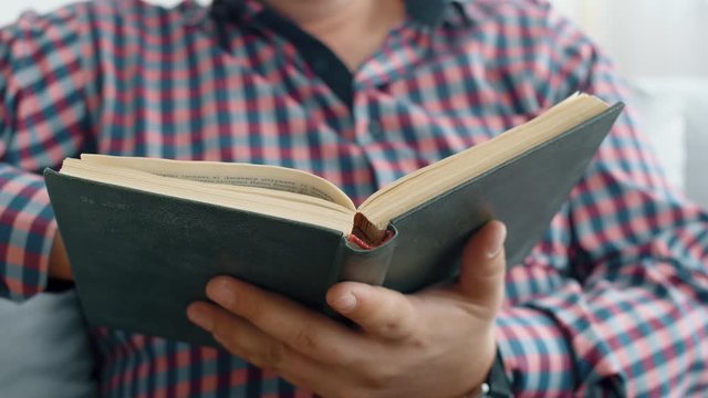 Man read interesting book on office table. Close up 4k slow motion footage.