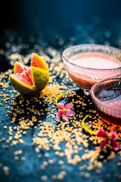 Guava face mask for dry skin on a wooden surface with vivid colors i.e., guava pulp, egg yolk, oatmeal, and some raw organic honey well mixed in a glass bowl along with raw ones.