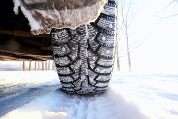 winter tires with spikes on the snow / transport road northern wheels, climate winter season - obrazy, fototapety, plakaty