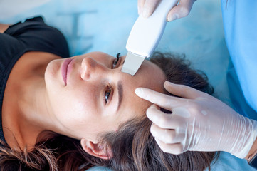 Fototapeta premium cosmetologist with a patient during facial procedures in a modern cosmetological and aesthetic clinic. A patient receives an electric facial massage. Skin rejuvenation and wrinkle smoothing.