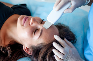 Naklejka premium cosmetologist with a patient during facial procedures in a modern cosmetological and aesthetic clinic. A patient receives an electric facial massage. Skin rejuvenation and wrinkle smoothing.
