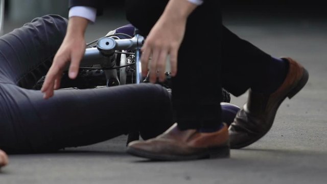 Young man checking wrist pulse of unconscious female bicyclist lying on asphalt