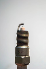 a close up of a used automotive spark plug on white background