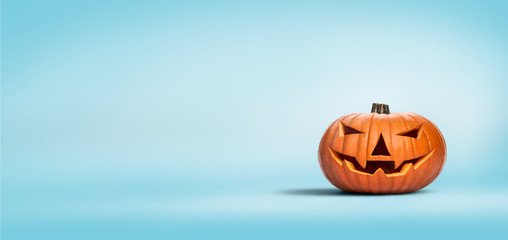 An unlit Halloween Jack O Lantern isolated on a widescreen pale blue background