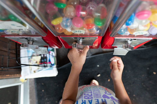 Child Placing a Quarter in Arcade Vending Machine
