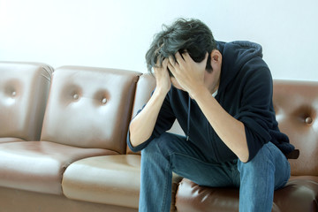 depressed man sitting on brown sofa and feeling sad