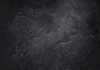 Abstract decorative textured dark black background with beautiful gray spots, strokes and stains. Texture of wall with decorative plaster on plywood, copy space.