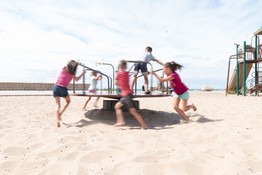 Children Playing on Merry Go Round at a Beach