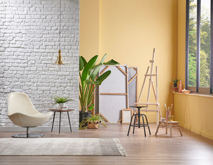 White brick wall and yellow background interior style, lamp frame chair and easel decor, home decoration interior.