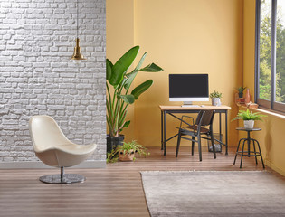 Modern yellow wall background and white brick wall style, wooden working table computer style, easel painting decoration vase of plant.