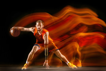 Becoming a winner. Young caucasian basketball player of red team in action and jump in mixed light...