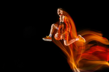 High flight. Young caucasian basketball player of red team in action and motion in mixed light over...
