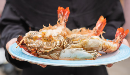Delicious big fresh grilled prawn or shrink in a dish hold by hand.