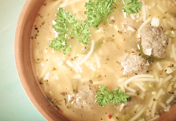 Homemade soup with noodles and meatballs on a wooden table. Traditional rural dinner. Toned
