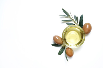 Bunch of local produce Turkish green gemlik olives with glass cup of extra virgin golden oil and olea europaea tree leaves. Close up, top view, copy space, isolated white background.