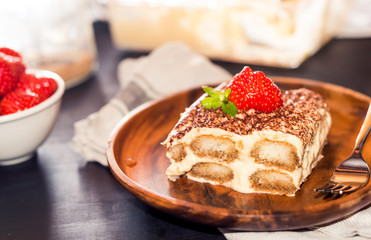 gourmet tiramisu dessert with strawberries in a beautiful plate on a dark background