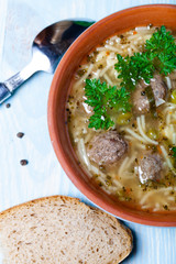 Homemade soup with noodles and meatballs on a wooden table. Traditional rural dinner