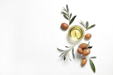 Bunch of local produce Turkish green gemlik olives with glass cup of extra virgin golden oil and olea europaea tree leaves. Close up, top view, copy space, isolated white background.