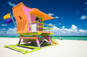 Vibrant sunny view lifeguard tower painted bright colors under blue sky on South Beach, Miami,...