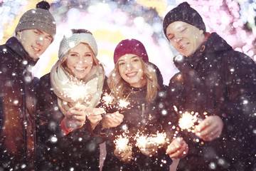 group of young people with sparklers Christmas party winter snow city