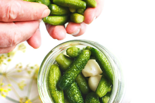 pickled cucumbers in a glass jar. gherkins cucumbers. woman pickles cucumbers on a white background