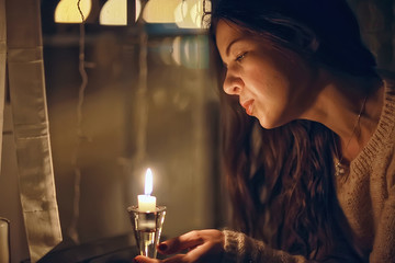 girl at the window dreams in winter evening / the romance of candle, the beautiful model in Christmas evening dreams