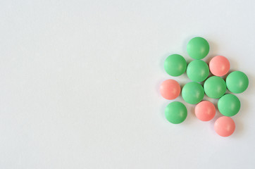 Heap of green and pink pills on a white background. Closeup of medicines. Copy space. Top view
