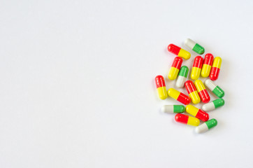 Heap of multi-colored capsules on a white background. Closeup of medicines. Copy space. Top view