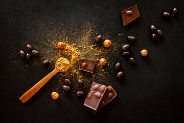 Chocolate bars and nuts on black table background top view