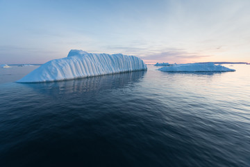 Photogenic and intricate iceberg under an interesting and blue sky during sunset. Effect of global...