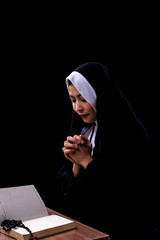 Portrait of nun is praying and reading scripture on black background