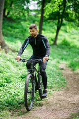 Fototapeta na wymiar Mountain bike cyclist riding single track outdoor with green park on background