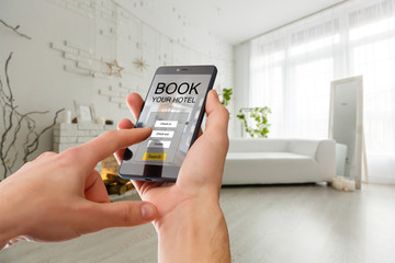 holding a smчartphone with booking hotel room app on screen for make reservation