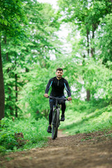 Mountain bike cyclist riding single track outdoor with green park on background