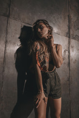 Fototapeta premium Fashion woman portrait in lingerie, shorts and handkerchief. Stylish beauty girl on metallic wall in loft room. Sexy seductive brunette model.