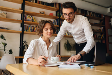 Young attractive business colleagues happily working on new project together in office