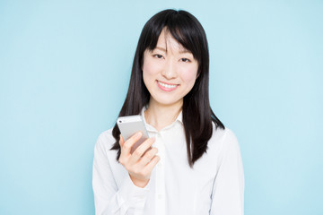 Young business woman holding smart phone against light blue background