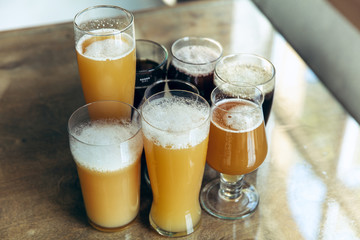 Top view of glasses of dark and light beer and ale on brick wall background. Cold delicious alcohol drinks are prepared for a big friend's party. Concept of holiday, fun, meeting, oktoberfest.