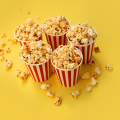 five red-and-white paper cups with popcorn on a yellow backgroun