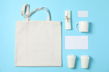 Flat lay composition with cotton bag, paper cups and office supplies on blue background