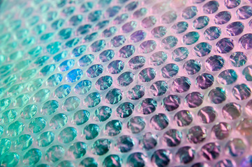 Holographic background in the style of the 80-90s. Real texture of bubble wrap film in bright acid...