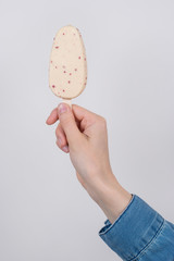 Vertical close up photo of arm holding tasty yummy delicious dessert for children isolated grey background