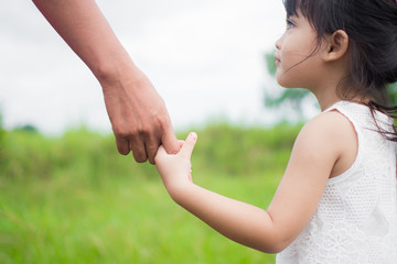a parent holds the hand of a small child with natre background. soft focus.