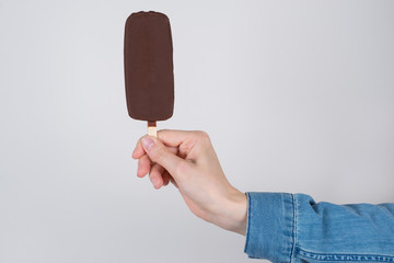 Side profile cropped pov first person close up photo of hand in casual jeans denim shirt clothes holding brown ice cream isolated grey background