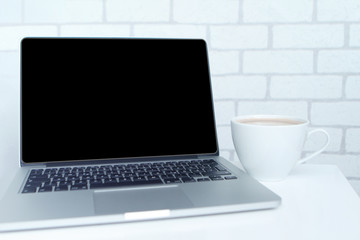 Mock up concept of remote work, downshifting using laptop with blank black desktop screen with a cup of coffee