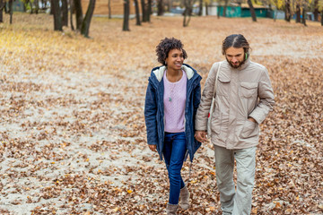 guy with an african american girl in love in autumn park walk at sunset