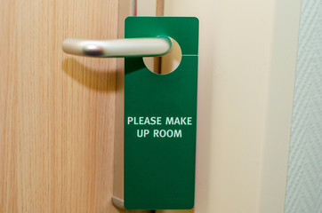 Closed door of hotel room with please make up room sign